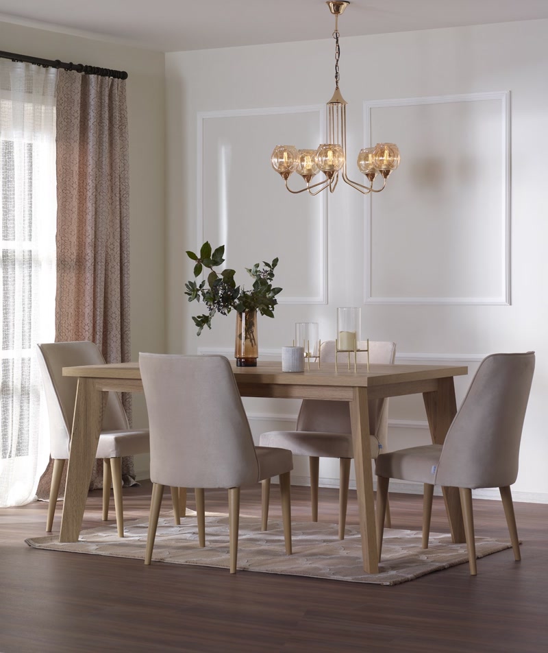 Profil Poliuretan P85008 pentru Decorare Pereti Sufragerie Profilul poliuretanic P85008 este un element decorativ din spumă poliuretanică de înaltă densitate (150-220 kg/m³ (țintă ~160 kg/m³)), destinat creării de casete și ancadramente pe pereții interiori. În această amenajare de sufragerie din zonă rezidențială, profilele P85008 sunt montate sub formă de panouri dreptunghiulare simetrice pe suprafața peretelui din spatele mesei. Materialul poliuretanic oferă o rezistență excelentă la impact și o absorbție de apă de sub 0,5%, prevenind umflarea sau deformarea cauzată de variațiile de umiditate din încăpere.

Tehnicile de montaj pentru profilul poliuretanic P85008 implică debitarea la unghi de 45 de grade a colțurilor folosind o cutie de tăiat sau un ferăstrău de miter manual. Fixarea pe placa de gips-carton sau tencuială se realizează utilizând un adeziv de montaj pe bază de polimeri, care asigură o priză inițială rapidă și o lipire definitivă în 24 de ore. Îmbinările dintre profile se sigilează cu un adeziv special pentru rosturi poliuretanice, prevenind apariția fisurilor în timp datorate dilatării termice în intervalul de funcționare de la -100 °C la +80 °C.

După întărirea adezivului, suprafața îmbinărilor se finisează prin șlefuire ușoară cu hârtie abrazivă de granulație 180-240 pentru a obține o tranziție perfect plană. Suprafața profilului P85008 este pre-amorsată din fabrică, permițând aplicarea directă a vopselei lavabile pe bază de apă, acrilice sau latex, în două straturi, fără pregătiri suplimentare. Această proprietate accelerează ritmul de execuție pe șantier comparativ cu stucaturile tradiționale din ipsos care necesită uscare îndelungată.

Spre deosebire de profilele din MDF sau lemn, poliuretanul dur nu își modifică volumul la variațiile de temperatură și nu este atacat de mucegai sau bacterii. Structura sa omogenă permite realizarea unor linii liniare precise pe perete, integrându-se impecabil în ansamblul decorativ al spațiului. Utilizarea profilelor P85008 în casete verticale oferă un efect vizual de alungire a spațiului, fiind o opțiune preferată de echipele de amenajări interioare pentru proiecte rezidențiale de tip vilă.