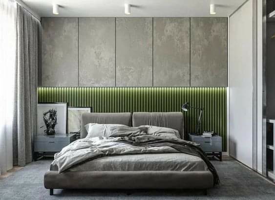Panouri Poliuretan Decorativ Modern pentru Perete Dormitor Panourile din poliuretan de înaltă densitate (P851350BU) reprezintă o soluție tehnică avansată pentru finisarea pereților interiori în dormitoare moderne, oferind o densitate de peste 150-220 kg/m³ (țintă ~160 kg/m³) și rezistență mecanică sporită. Aceste elemente decorative preiau textura betonului aparent fără a încărca structura de rezistență a clădirii, având o greutate redusă față de betonul turnat tradițional. Sistemul modular permite montajul rapid pe suprafețe tencuite, gips-carton sau lemn, asigurând o stabilitate dimensională excelentă în plaja de temperaturi de la -100 °C / +80 °C.

Procesul de instalare al panourilor poliuretanice necesită utilizarea unui adeziv structural pe bază de polimeri hibrizi pentru o fixare rigidă și durabilă. Rosturile dintre plăci se tratează cu adeziv special de îmbinare, urmat de o șlefuire ușoară cu hârtie abrazivă cu granulație 240 pentru obținerea unei suprafețe perfect uniforme. Datorită coeficientului de absorbție a apei de sub 1%, poliuretanul nu suferă modificări structurale în prezența umidității ambientale, prevenind apariția fisurilor sau a deformațiilor în timp.

În configurația prezentată, placarea din poliuretan este combinată în zona inferioară cu profile verticale din lemn sau MDF, creând un contrast vizual și tactil bine echilibrat. Nișa creată la linia de îmbinare integrează un profil din aluminiu cu bandă LED de joasă tensiune, asigurând o disipare termică optimă și o iluminare indirectă omogenă. Polimerul spumat permite tăierea facilă la dimensiune folosind scule obișnuite de tâmplărie, facilitând adaptarea la doze, întrerupătoare sau casete electrice încastrate.

Față de finisajele clasice din tencuială decorativă sau plăci ceramice grele, panourile decorative poliuretanice asigură o izolare fonică suplimentară și un timp de punere în operă redus cu până la 50%. Materialul este pregătit din fabrică cu un strat de grund acrilic, permițând vopsirea ulterioară în orice nuanță dorită cu vopsele pe bază de apă. Această abordare tehnică oferă constructorilor și echipelor de amenajări o metodă eficientă, curată și reproductibilă de a crea perete accent în spații rezidențiale.