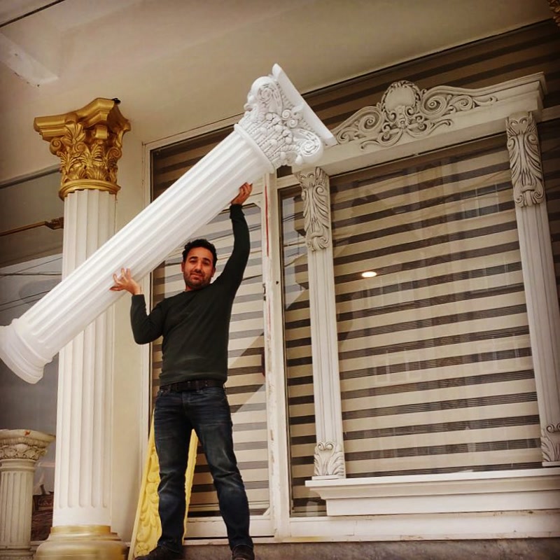 Coloane și Profiluri din Poliuretan pentru Fațade Clasice Coloanele și profilele arhitecturale din poliuretan de înaltă densitate reprezintă soluții tehnice moderne pentru decorarea fațadelor clasice fără a supragrena structura de rezistență a clădirii. În comparație cu elementele tradiționale din beton sau ipsos care pot cântări zeci de kilograme, o coloană decorativă din poliuretan cu o densitate de 150-220 kg/m³ (țintă ~160 kg/m³) oferă o manipulare facilă și un montaj extrem de rapid. Această greutate redusă permite instalarea directă pe sistemele de izolație termică existentă fără ancorări structurale grele sau modificări ale proiectului de rezistență.
Procesul de montaj al ancadramentelor și al coloanelor din poliuretan se bazează pe utilizarea adezivilor poliuretanici structurali și fixare mecanică secundară. Îmbinările dintre profile se realizează prin lipire cu adeziv special de îmbinare, urmată de șlefuire cu hârtie abrazivă de granulație 180-240 pentru a obține o suprafață perfect continuă. Datorită stabilității dimensionale ridicate, elementele decorative nu crapă la schimbările de temperatură și asigură o etanșeitate excelentă împotriva infiltrațiilor de apă la nivelul ferestrelor.
Materialul poliuretanic prezintă o rată de absorbție a apei de sub 0.5%, ceea ce îl face complet imun la ciclurile de îngheț-dezgheț și la degradarea cauzată de umiditate. De asemenea, proprietățile fizice rămân stabile într-un interval termic extins, de la -100 °C / +80 °C, prevenind deformările structurale pe fațadele expuse la soare direct. Suprafața pre-amorsată din fabrică oferă o aderență optimă pentru aplicarea vopselelor lavabile de exterior pe bază de acril sau silicon, permițând finisaje în culori variate sau decorări cu foiță de aur.
Alegerea sistemelor decorative din poliuretan optimizează semnificativ timpul de execuție pe șantier și reduce costurile cu forța de muncă specializată. Lipsa necesității echipamentelor de ridicare grele simplifică logistica, iar durabilitatea pe termen lung elimină lucrările frecvente de întreținere sau reparații. Profilele folosite în jurul ferestrelor și coloanele de susținere decorativă adaugă valoare tehnică și estetică proiectelor rezidențiale sau comerciale, menținând totodată o izolație termică suplimentară pe fațadă.