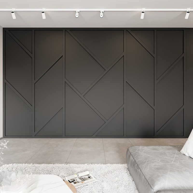 Profil Poliuretan P851350 cu Design Geometric Asimetric Profilul din poliuretan P851350 este un element decorativ de înaltă densitate, utilizat în amenajările interioare pentru crearea de panouri geometrice și placări decorative pe suprafețele verticale. În proiectul prezentat, acest profil îngust și liniar este montat pe un perete principal de accent finisat în nuanță închisă de antracit, unde liniile diagonale și verticale formează o rețea asimetrică tridimensională. Densitatea ridicată a materialului, cuprinsă între 180 și 150-220 kg/m³ (țintă ~160 kg/m³), garantează o rezistență excelentă la lovituri mecanice, menținând totodată o greutate redusă care facilitează fixarea rapidă pe perete.

Procesul de montaj al profilelor din poliuretan P851350 necesită o debitare de precizie la unghiuri variabile de 45 sau 90 de grade, utilizând o retezătoare circulară cu disc fin pentru polimeri. Lipirea pe suportul din zidărie sau gips-carton se efectuează folosind un adeziv polimeric monocomponent cu aderență inițială puternică, iar îmbinările dintre baghete se sigilează cu un adeziv special pentru rosturi. După uscarea completă, rosturile se șlefuiesc ușor cu hârtie abrazivă de granulație 240 pentru a obține o continuitate perfectă. Materialul prezintă o rată de absorbție a apei de sub 1%, fiind stabil dimensional la variații de temperatură între -100 °C / +80 °C.

După finalizarea etapei de îmbinare și șlefuire, suprafața profilului din poliuretan este pregătită pentru aplicarea finisajului protector. Deoarece profilele sunt pre-amorsate din fabrică cu un strat alb solubil în apă, peste ele se poate aplica direct vopsea lavabilă acrilică sau poliuretanică în 2 straturi succesive. În această configurare, peretele și profilele P851350 au fost vopsite unitar în aceeași culoare mată, eliminând vizual întreruperile și accentuând jocul natural de umbre creat de iluminatul direcțional cu spoturi LED montate pe șină.

Spre deosebire de profilele clasice din lemn sau ipsos, poliuretanul de înaltă densitate nu crapă la schimbările de umiditate și nu necesită armare suplimentară. Flexibilitatea moderată a profilului P851350 permite preluarea micilor imperfecțiuni ale peretelui fără a compromite aliniamentul rețelei geometrice. Utilizarea acestui tip de baghetă decorativă în proiecte rezidențiale sau comerciale oferă o soluție durabilă, ușor de întreținut și rapid de pus în operă de către echipele de finisaje interioare.