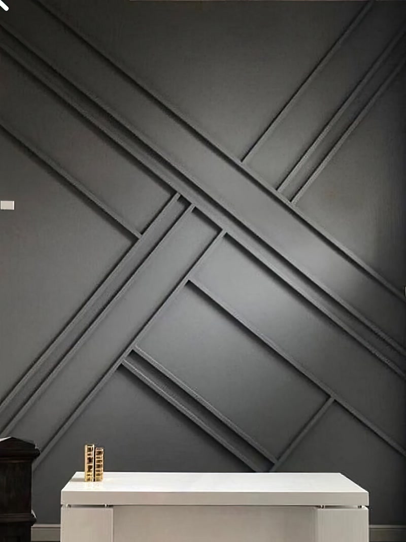 Poliuretan Baghetă Decorativă și Profil perete P851350 Profilul din poliuretan P851350 este un element decorativ de înaltă densitate, conceput pentru crearea de panouri geometrice și placări decorative pe suprafețe verticale interioare. În proiectele tehnice de amenajare, acest profil oferă o densitate ridicată de aproximativ 150-220 kg/m³ (țintă ~160 kg/m³), garantând o rezistență mecanică sporită la impact și stabilitate dimensională în timp. Spre deosebire de MDF sau lemn, poliuretanul nu absoarbe umiditatea, având o rată de absorbție a apei sub 1%, ceea ce împiedică dilatarea sau deformarea îmbinărilor pe perete.

Aplicarea structurii geometrice asimetrice necesită o trasare precisă cu nivelă laser și tăierea profilului P851350 la unghiuri variabile de 45° și 90°. Pentru o fixare structurală fermă, se utilizați un adeziv poliuretanic monocomponent sau hibrid, aplicat în cordon continuu pe spatele profilului. Rosturile dintre baghete se umplu cu un mastic acrilic flexibil special pentru poliuretan, lăsând o toleranță de montaj de 1-2 mm la îmbinări pentru a prelua eventualele mișcări micro-structurale ale clădirii.

După procesul de polimerizare a adezivului de aproximativ 24 de ore, îmbinările sunt șlefuite fin cu hârtie abrazivă de granulație 240 pentru a obține o suprafață perfect continuă. Materialul poliuretanic vine pre-amorsat din fabrică cu un strat alb pe bază de apă, pregătit pentru vopsire directă. În acest design, suprafața a fost acoperită uniform cu o vopsea lavabilă mată în nuanță gri antracit, aplicată în 2 straturi prin pulverizare sau cu trafalet cu fir scurt, rezultând un finisaj omogen fără urme de pensulă.

Din punct de vedere executiv, utilizarea profilelor din poliuretan P851350 reduce timpul de instalare cu până la 40% comparativ cu stucaturile clasice din ipsos sau profilaturile grele din lemn. Rezistența termică cuprinsă între -100 °C / +80 °C permite utilizarea acestora în spații rezidențiale și comerciale cu solicitări variate. Această soluție tehnică oferă constructorilor și montatorilor o modalitate rapidă, curată și durabilă de a realiza pereți accent cu impact vizual deosebit.