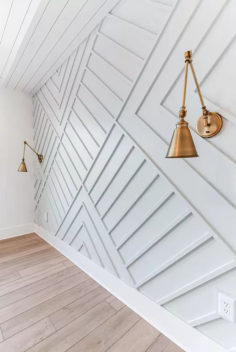 Montaj Profil Poliuretan P851350 Pentru Perete Geometric Aplicația de stucatură din profil poliuretan P851350 reprezintă o soluție tehnică avansată pentru finisarea spațiilor interioare prin realizarea de modele geometrice tridimensionale pe pereții de accent. Densitatea ridicată a spumei poliuretanice de înaltă calitate, situată la valoarea de 150-220 kg/m³ (țintă ~160 kg/m³), garantează o rezistență mecanică sporită la lovituri accidentale și o stabilitate dimensională impecabilă în timp. Spre deosebire de profilele tradiționale din ipsos sau MDF, poliuretanul prezintă o rată de absorbție a apei de sub 1%, ceea ce elimină complet riscul de umflare, mucegai sau deformare cauzată de variațiile de umiditate din mediul ambiant.

Execuția montajului pentru un perete decorativ cu relief asimetric impune respectarea unui protocol tehnic strict de trasare și debitare. Înainte de lipire, suprafața zidăriei trebuie curățată, amorsată și nivelată corespunzător. Debitarea profilului poliuretan P851350 se efectuează cu un ferăstrău mecanic cu pânză fină, executând tăieturi la unghiuri de 45 sau 30 de grade, în funcție de geometria schiței de proiect. Fixarea pe perete se face prin aplicarea unui adeziv structural acrilic cu priză rapidă pe spatele profilului, iar pentru îmbinările dintre baghete se folosește un adeziv special pentru rosturi, lăsând un spațiu de dilatare controlat de 1-2 mm.

Comportamentul materialului la finisărileulterioare reprezintă un element crucial pentru echipele de meșteri și montatori profesioniști. Deoarece profilele din poliuretan beneficiază de o amorsare din fabrică cu un strat alb mat, acestea oferă o aderență optimă pentru vopselele lavabile pe bază de apă, latex sau acril. Datorită rezistenței termice excelente în intervalul de temperatură -100 °C / +80 °C, profilele pot fi instalate fără probleme în imediata apropiere a corpurilor de iluminat de perete, cum sunt aplicele din alama montate direct peste structura decorativă, fără pericol de decojire sau fisurare.

Folosirea profilului poliuretan P851350 într-un ansamblu geometric complex transformă suprafața plană a peretelui dintr-un salon modern într-o structură arhitecturală definită prin linii dinamice și jocuri de umbre. Flexibilitatea de configurare le permite constructorilor să mascheze eficient micile imperfecțiuni ale tencuielii existente, oferind în același timp o soluție durabilă și ușor de întreținut. Eficiența procesului de instalare, greutatea redusă a elementelor și finisajul impecabil fac din profilele poliuretanice opțiunea preferată în proiectele de amenajare de înaltă precizie.