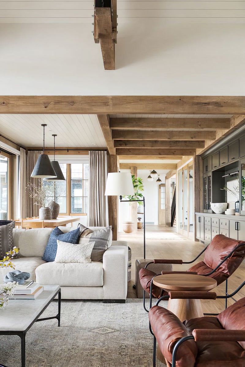 Montaj Grinzi si Capriori din Poliuretan Stil Rustic Grinzile decorative din poliuretan reprezintă soluții structurale aparente destinate finisării plafoanelor în proiectele rezidențiale de tip vilă. În acest proiect de amenajare interioară, s-a utilizat un sistem complex format din profilele din poliuretan P1981E, P1981F și P1981K, recunoscute pentru imitarea fidelă a texturii de lemn masiv cioplit. Spre deosebire de grinziile naturale din lemn care pot adăuga o încărcare structurală de peste 50 kg pe metru liniar, profilele din spumă poliuretanică de înaltă densitate (150-220 kg/m³ (țintă ~160 kg/m³)) oferă o alternativă ușoară și stabilă dimensional. Această proprietate elimină necesitatea ranforsării suplimentare a structurii de rezistență a plăcii din beton sau a tavanului din gips-carton.

Fixarea profilelor decorative pe tavan și pe stâlpii de susținere se realiză prin lipire structurală cu adeziv poliuretanic monocomponent și fixare mecanică secundară. La îmbinările dintre grinzi (P1981E) și căpriori (P1981F), montatorii aplică adeziv de îmbinare special pe bază de poliuretan pentru a preveni apariția fisurilor în timp. Toleranța de dilatare termică a materialului este extrem de redusă la temperaturi cuprinse între -100 °C / +80 °C, asigurând stabilitatea îmbinărilor pe termen lung. Pentru realizarea stâlpilor verticali (P1981K), profilele în formă de U sunt îmbrăcate peste nucleul structural sau ghidaje metalice, mascând eficient cablurile electrice sau țevile de instalații.

Un avantaj tehnic major al elementelor din poliuretan este rata de absorbție a apei de sub 1%, ceea ce le face imune la deformările cauzate de variațiile de umiditate din încăpere. Lemnul masiv tinde să crăpe sau să se torsioneze în timp, însă profilele din poliuretan își mențin geometria intactă indiferent de anotimp. Textura de suprafață este pre-grunduită din fabrică, permițând aplicarea facilă a vopselelor pe bază de apă, acrilice sau baițurilor speciale pentru obținerea nuanțelor dorite de stejar rustic, nuc sau patina învechită. În plus, șlefuirea fină cu hârtie abrazivă de granulație 220 înainte de vopsire asigură o aderență optimă a stratului final.

Utilizarea grinzilor din poliuretan P1981E, P1981F și P1981K eficientizează considerabil timpul de execuție pe șantier, reducând manopera cu până la 60% comparativ cu prelucrarea și instalarea lemnului masiv. Montajul nu necesită scule grele sau utilaje de ridicat, fiind realizat rapid de o echipă formată din doi meșteri. Această soluție este ideală pentru firmele de construcții și amenajări interioare care doresc să ofere clienților un finisaj rustic impecabil, durabil și fără riscuri de crapare în timp.