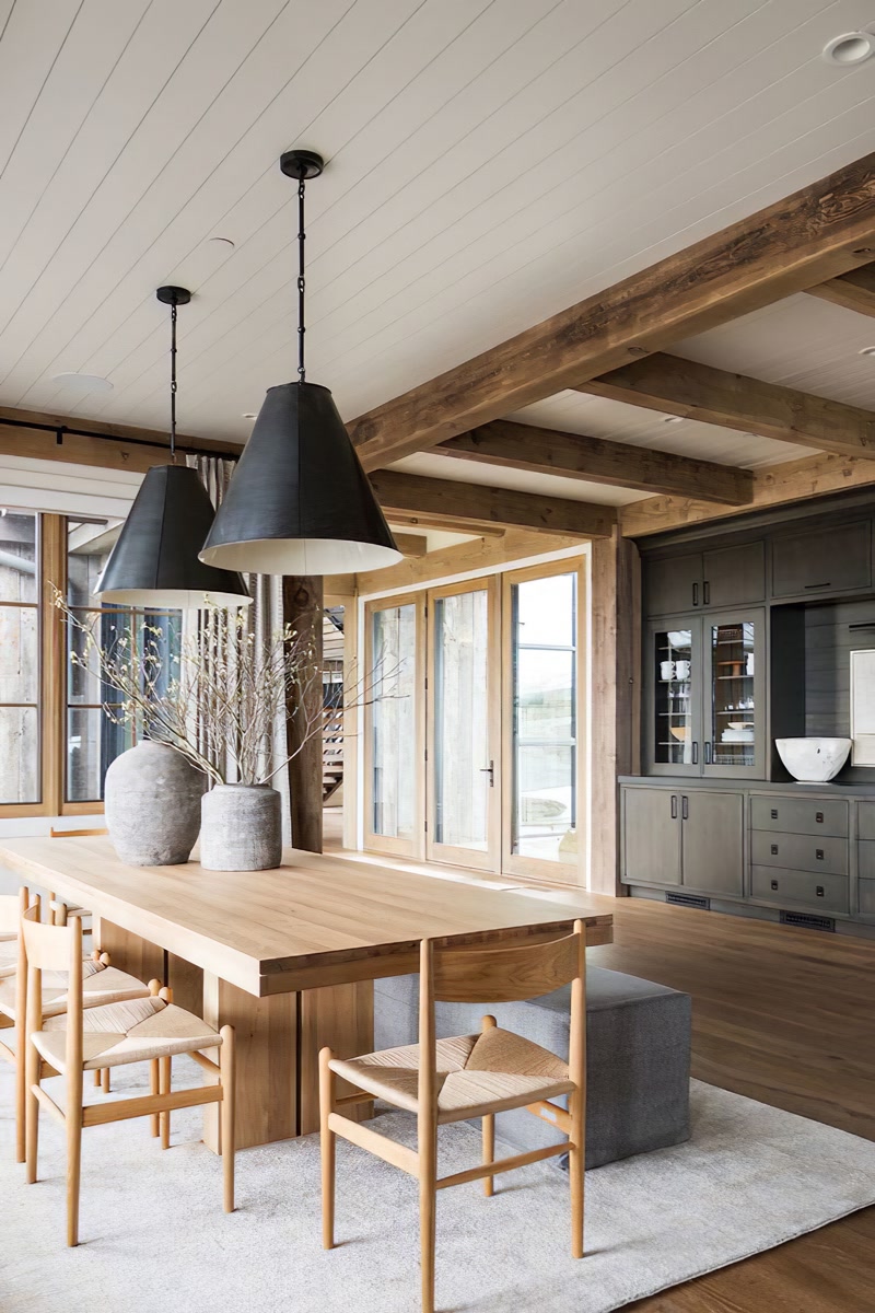 Grinzi Poliuretan Decorative Pentru Tavane Structurale Grinzile din poliuretan sunt elemente decorative ușoare destinate simulării structurilor din lemn masiv pe tavane și pereți interiori, fără a supune structura clădirii la sarcini suplimentare. În amenajarea din imagine, sistemul de grinzi din colecția P1981, incluzând profilele P1981B, P1981C, P1981D și elementele de îmbinare P1981BK sau P1981CK, creează o casetare rustică pe un tavan placat cu lambriuri albe. Spre deosebire de grindă din lemn natural de stejar sau brad, poliuretanul de înaltă densitate de aproximativ 150-220 kg/m³ (țintă ~160 kg/m³) permite montajul rapid prin lipire adezivă și fixare mecanică discretă, eliminând riscul de deformare în timp din cauza variațiilor de umiditate.

Fixarea grinzilor poliuretanice pe tavanul finisat se realizează prin utilizarea unor șipci din lemn de ghidaj ancorate la intervale de 60 cm pe suprafața suport. Profilele profilate în formă de U se îmbină peste aceste șipci, fiind fixate cu adeziv poliuretanic de montaj și șuruburi al căror cap este ulterior mascat cu chit acrilic. Accesoriile dedicate de tip console sau conectori precum P1981BKA, P1981CKA și P1981DKA acoperă eficient punctele de îmbinare cap la cap ale grinzilor, garantând un finisaj continuu și rezistent la fisuri mecanice. Stratul exterior este pre-finit sau poate fi vopsit cu vopsele pe bază de apă pentru potrivirea nuanței exacte a tâmplăriei.

Din punct de vedere al comportamentului materialului, spuma rigidă de poliuretan oferă o rezistență termică excelentă în plaja de temperaturi de la -100 °C / +80 °C și un coeficient de absorbție a apei de sub 1%. Această stabilitate dimensională previne apariția spațiilor între grindă și tavan sau crăparea îmbinărilor în spații cu variații sezoniere de temperatură, cum sunt zonele de dining deschise către terase sau livingurile cu vitraje mari. În plus, greutatea redusă de doar 1,5 kg până la 3 kg pe metru liniar simplifică manipularea pe șantier și reduce timpii de manoperă cu până la 50% comparativ cu instalarea grinzilor din lemn masiv uscat.

Integrarea grinzilor decorative din poliuretan în proiectele comerciale sau rezidențiale de mari dimensiuni permite trecerea facilă a cablurilor electrice sau a traseelor de iluminat direct prin interiorul gol al profilelor. Această proprietate tehnică facilitează mascarea cablajelor pentru sistemele de iluminat suspendat, așa cum sunt lustrele masive din imagine, fără a necesita canale în zidărie sau tavane false coborâte suplimentar. Pentru meșteri și echipe de renovare, utilizarea colecției P1981 reprezintă o soluție tehnică curată, durabilă și conformă cu standardele moderne de eficiență în construcții.