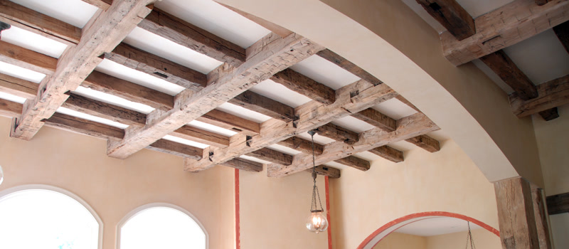 Grinzi Decorative din Poliuretan pentru Plafon Structurat Grinzile decorative din poliuretan reprezintă o soluție tehnologică avansată pentru realizarea structurilor de plafon casetat cu aspect rustic, fără a încărca structura de rezistență a clădirii. Cu o densitate medie cuprinsă între 150-220 kg/m³ (țintă ~160 kg/m³), aceste elemente din polimer de înaltă densitate oferă o reducere a greutății de peste 85% comparativ cu grinzi masive din lemn natural. Această proprietate simplifică semnificativ manipularea pe șantier și permite montajul direct pe tavane din gips-carton sau tencuială existentă. Materialul prezintă o rată de absorbție a apei de sub 1%, prevenind deformarea sau fisurarea în timp cauzată de fluctuațiile de umiditate din încăpere.

Procesul de instalare a rețelei casetate utilizând profile din seria P1981 (cum ar fi P1981B, P1981C și P1981D) se bazează pe fixarea prealabilă a unor șipci din lemn de ghidaj pe suprafața plafonului. Profilele U din poliuretan sunt ulterior îmbinate peste aceste șipci prin lipire cu adeziv poliuretanic structural și ancorare mecanică discretă. Toleranța termică a materialului, cuprinsă între -100 °C / +80 °C, asigură stabilitatea dimensională a îmbinărilor chiar și în spații expuse la variații sezoniere de temperatură sau la căldura generată de corpurile de iluminat suspendate.

Realizarea rețelei ortogonale necesită tăieri precise la unghi de 45 de grade sau îmbinări de tip T, unde elementele de legătură (precum P1981BK sau P1981DK) maschează zonele de tăiere și absorb imperfecțiunile liniare ale tavanului. Îmbinările dintre profile sunt etanșate cu chit poliuretanic flexibil și șlefuite cu hârtie abrazivă de granulație 220 înainte de aplicarea baitului sau a vopselei de finisaj. Această abordare elimină riscul apariției fisurilor la îmbinări și garantează o continuitate vizuală impecabilă a texturii lemnoase pe întreaga suprafață a tavanului.

Pentru firmele de amenajări și montatori, utilizarea grinzilor din poliuretan optimizează timpul de execuție al proiectului cu până la 60% în comparație cu dulgheria tradițională. Lipsa necesității de uscare sau tratament anticarii reduce costurile operaționale și riscul de garanție post-montaj. În plus, profilul gol la interior permite mascarea facilă a cablajelor electrice, traseelor HVAC sau iluminatului ambiental integrat, oferind o soluție tehnică completă pentru spații rezidențiale sau comerciale.