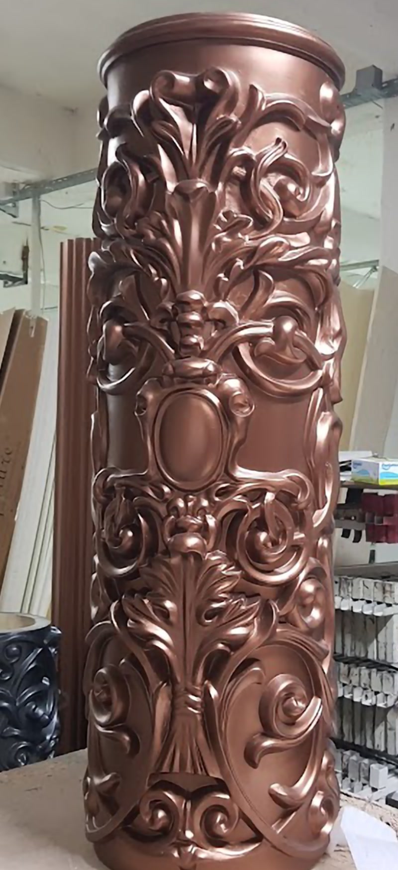 Coloană Poliuretan Sculptată P5540 cu Finisaj Bronz Coloana din poliuretan model P5540 reprezintă un element decorativ arhitectural de înaltă densitate (aproximativ 150-220 kg/m³ (țintă ~160 kg/m³)), proiectat pentru îmbrăcarea sau crearea structurilor verticale decorative în amenajările interioare. Procedeul de turnare în matrițe industriale de înaltă precizie permite obținerea unor basoreliefuri profunde și detaliate de inspirație barocă, menținând în același timp o greutate structurală redusă comparativ cu ipostasurile clasice din beton sau ipsos. Datorită structurii cu celule închise, coeficientul de absorbție a apei este de sub 0,5%, ceea ce previne umflarea, fisurarea sau degradarea materialului în spații cu umiditate variabilă.

Montajul coloanei din poliuretan P5540 necesită utilizarea unui adeziv structural pe bază de poliuretan sau polimeri hibrizi, aplicat într-un strat omogen de 2-3 mm pe suprafețele de contact. Datorită rezistenței termice cuprinse între -100 °C / +80 °C, materialul nu suferă dilatări liniare majore, garantând o stabilitate dimensională pe termen lung. Pentru fixarea secțiunilor sau îmbinărilor verticale, se recomandă utilizarea adezivului special pentru îmbinări poliuretanice, urmată de șlefuirea fină cu abraziv de granulație 240 sau 320 înainte de aplicarea grundului de aderență.

Finisarea suprafeței sculptate a modelului P5540 din poliuretan se realizează prin aplicarea vopselelor acrilice sau pe bază de apă, urmate de tehnici speciale de patinare metalică precum efectul de bronz satinat. Structura densă a poliuretanului împiedică absorbția neuniformă a pigmenților, permițând obținerea unor contraste pronunțate între zonele de relief adânc și suprafețele convexe ale acantului. În plus, suprafața este complet pregătită din fabrică cu un strat primar de grund, reducând consumul total de vopsea și timpul de uscare la doar câteva ore.

Alegerea coloanelor decorative din poliuretan P5540 în detrimentul alternativelor tradiționale din piatră sau ipsos aduce avantaje majore în privința vitezei de punere în operă și a sarcinilor structurale. Greutatea redusă nu solicită structura de rezistență a clădirii, permițând instalarea pe șape existente sau plafoane suspendate fără consolidări suplimentare. Materialul rezistă eficient la șocuri mecanice moderate, nu emite praf în timp și oferă o durabilitate superioară, fiind opțiunea preferată de meșteri și antreprenori în amenajări rezidențiale sau comerciale.