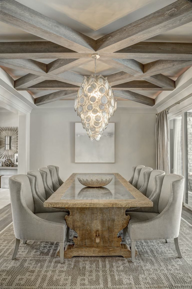 Montaj Grinzi din Poliuretan pe Tavan Casetat Rustic Grinzile decorative din poliuretan reprezintă profile arhitecturale de înaltă densitate, având o masă volumică de 150-220 kg/m³ (țintă ~160 kg/m³), concepute pentru realizarea plafoanelor casetate fără a aplica o încărcare structurală pe planșeu. În proiectul prezentat, grinzile din seria P1981 sunt dispuse într-un tipar geometric în formă de X, creând un plafon cu casete romboidale ce oferă adâncime spațiului de luat masa. Spre deosebire de grinzi tradiționale din lemn masiv care pot cântări zeci de kilograme pe metru liniar, profilele din spumă poliuretanică dură asigură o manipulare facilă și o ancorare sigură chiar și pe plafoane din gips-carton.
Tehnologia de instalare a grinzilor poliuretanice se bazează pe tăierea precisă la unghiuri compuse și îmbinarea mecanică dublată de lipire chimică. Pentru intersecțiile complexe la unghiuri ascuțite ale seriei P1981A-P1981L, se recomandă utilizarea unui fierăstrău de debitat cu ghidaj unghiular și adeziv poliuretanic de îmbinare structurală. Stabilitatea dimensională a materialului în intervalul de temperatură cuprins între -100 °C / +80 °C previne apariția fisurilor la rosturi, o problemă frecvent întâlnită în cazul lemnului supus variațiilor sezoniere de umiditate.
Din punct de vedere al comportamentului la mediu, poliuretanul prezintă un coeficient de absorbție a apei sub 1%, ceea ce elimină riscul de deformare, mucegai sau atac al insectelor xilofage. Suprafețele grinzilor pot fi șlefuite fin cu hârtie abrazivă de granulație 180-240 și finisate cu vopsele pe bază de apă, acrilice sau lazuri speciale pentru a imita textura patinată a lemnului băițuit. Această flexibilitate de finisare permite echipelor de montaj să potrivească nuanța tavanului cu restul elementelor din lemn din încăpere.
Pentru firmele de construcții și amenajări interioare, utilizarea grinzilor din poliuretan reduce timpul de execuție la tavan cu peste 60% comparativ cu dulgheria clasică. Canalele interioare goale ale profilului permit mascarea cablajelor electrice și integrarea facilă a sistemelor de iluminat suspendate sau încastrate. Soluția tehnică garantează o durabilitate de lungă durată fără necesitatea unor lucrări periodice de recondiționare sau tratamente ignifuge suplimentare.