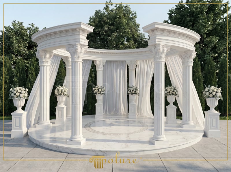 Poliuretan Coloane Decorative si Structura Gazebo Exterior Structura circulară de exterior realizată din coloane din poliuretan reprezintă o soluție tehnică avansată pentru spațiile de evenimente și foișoare ceremoniale. În această aplicație de foișor, coloanele din poliuretan de înaltă densitate, având o valoare de 150-220 kg/m³ (țintă ~160 kg/m³), oferă o rezistență mecanică sporită la factorii de mediu, înlocuind cu succes piatra sau marmura masivă. Polimerul rigid asigură o stabilitate dimensională excelentă în intervalul de temperatură cuprins între -100 °C / +80 °C, eliminând riscul de fisurare cauzat de ciclurile frecvente de îngheț-dezgheț. De asemenea, având o rată de absorbție a apei de sub 1%, materialul nu permite infiltrarea umidității, protejând structura de degradare pe termen lung.
Montajul tehnic al elementelor verticale se bazează pe modularitatea profilelor din poliuretan P5230C, P5230C50 și P5240C, combinate cu semicoloane și pilastri P5030BC. În interiorul carcasei tubulare din poliuretan se montează un miez structural de susținere din oțel galvanizat sau beton, care preia încărcările mecanice ale arhitravei curbate. Modulele de coloană, compuse din bază, fus canelat și capitel Corintic, se îmbină pe poziție folosind adezivi structurali poliuretanici cu timp rapid de priză. Rosturile dintre segmente se etanșează cu chit poliuretanic monocomponent, urmat de o șlefuire fină cu granulație de 180 pentru obținerea unei suprafețe omogene.
Sistemul include și coloanele de sprijin perimetrale P5830, P583050, precum și elementele de bază P5930B și P5930B50, fixate ancorat de placa de fundare prin dibluri mecanice de mare rezistență. Datorită greutății reduse a poliuretanului comparativ cu betonul turnat, eforturile pe fundație sunt reduse considerabil, facilitând o instalare rapidă fără echipamente grele de ridicare. Finisajul exterior se realizează prin aplicarea unei amorse acrilice de profunzime și a 2 straturi de vopsea elastomericā rezistentă la razele UV. Acest strat protector previne îngălbenirea materialului și permite o întreținere facilă prin spălare cu jet de apă sub presiune.
Integrarea perdelelor textile și a pieselor decorative suplimentare pe structura de arhitravă se face prin puncte de ancorare mecanice prevăzute direct în inserturile structurale interioare, prevenind tensionarea directă a mantalei din poliuretan. Rezultatul este o construcție arhitecturală durabilă, rezistentă la intemperii și atac fungic, optimizată pentru funcționarea pe termen lung în spații comerciale exterioare precum saloane de nunți sau grădini de evenimente.