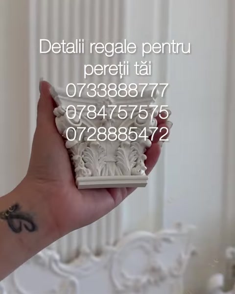 Mână ține un profil decorativ mic lângă coloană albă