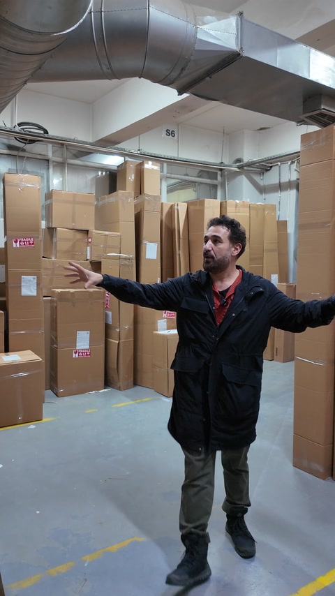 Bărbat în depozit cu cutii de carton stivuite