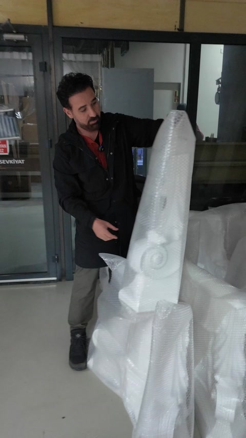 Bărbat cară un capitel mare ambalat spre expediere