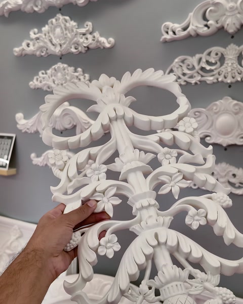 Mână care fixează un ornament decorativ din poliuretan pe perete