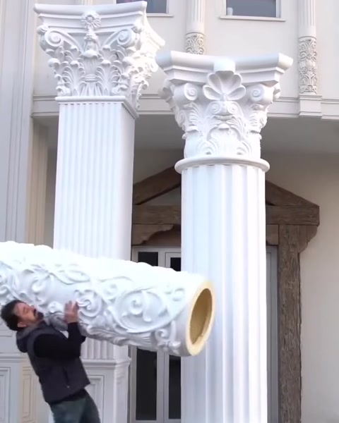 Muncitor cară o piesă cilindrică de capitel pe schelă