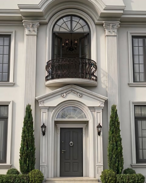 Fațadă albă cu ancadrament ornamentat la intrare și brâuri decorative