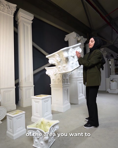 Capitel corintic ținut în mâini lângă coloana canelată din fundal
