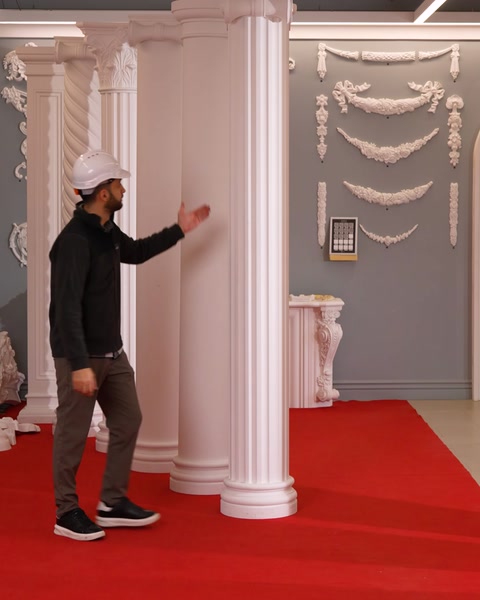 Meșter atinge o coloană lângă șemineu și ornamente de perete