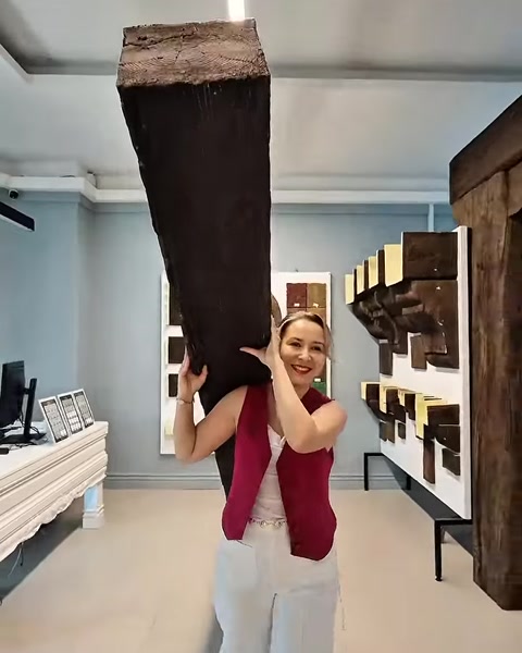 Femeie duce pe umăr o grindă poliuretanică cu efect antic, în showroom.