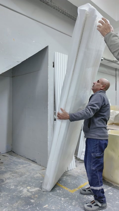 Doi muncitori ridică un panou decorativ înalt și profilat