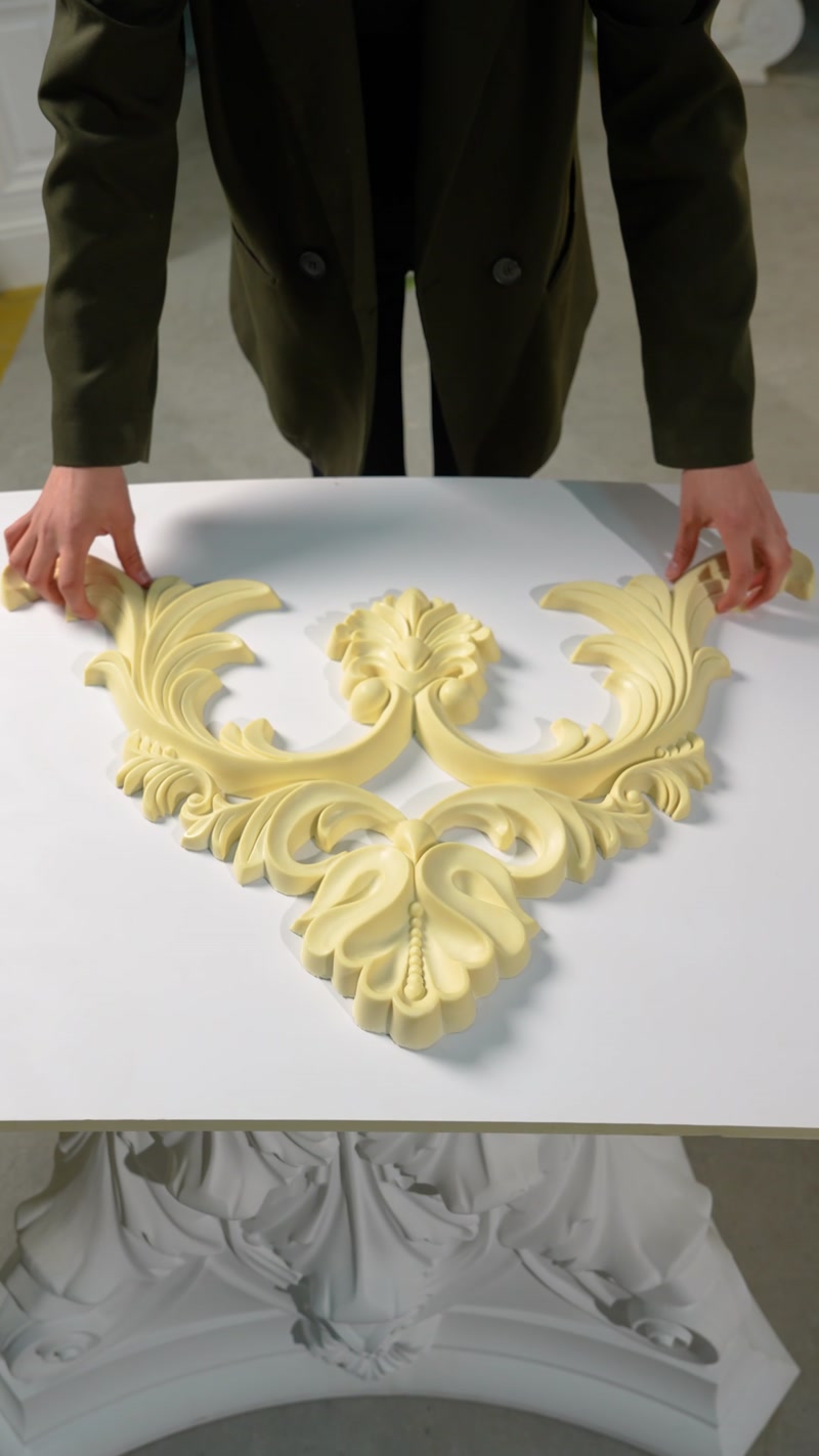 Mâini așază un ornament decorativ sculptat pe o masă albă
