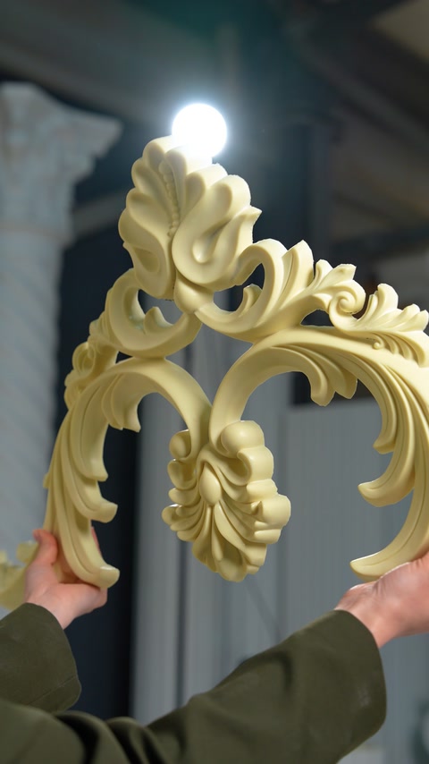 Mâini țin un ornament sculptat cu frunze de acant, în relief