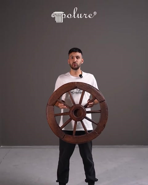 Bărbat ține o roată decorativă din lemn pentru exterior