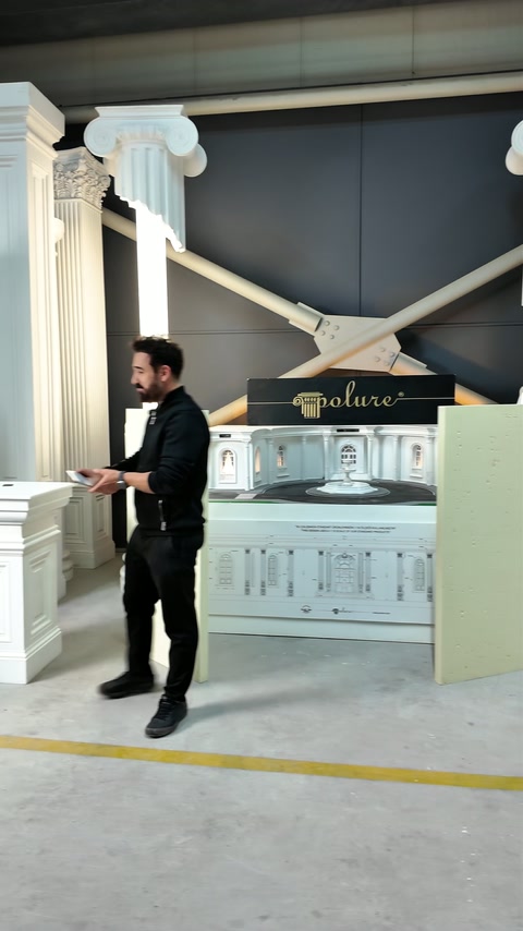 Prezentatorul explică proiectul lângă panouri și coloane decorative expuse.