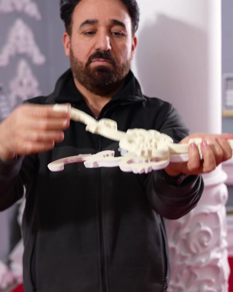 Piesa crem din turnare flexibilă ținută cu ambele mâini pentru îndoire